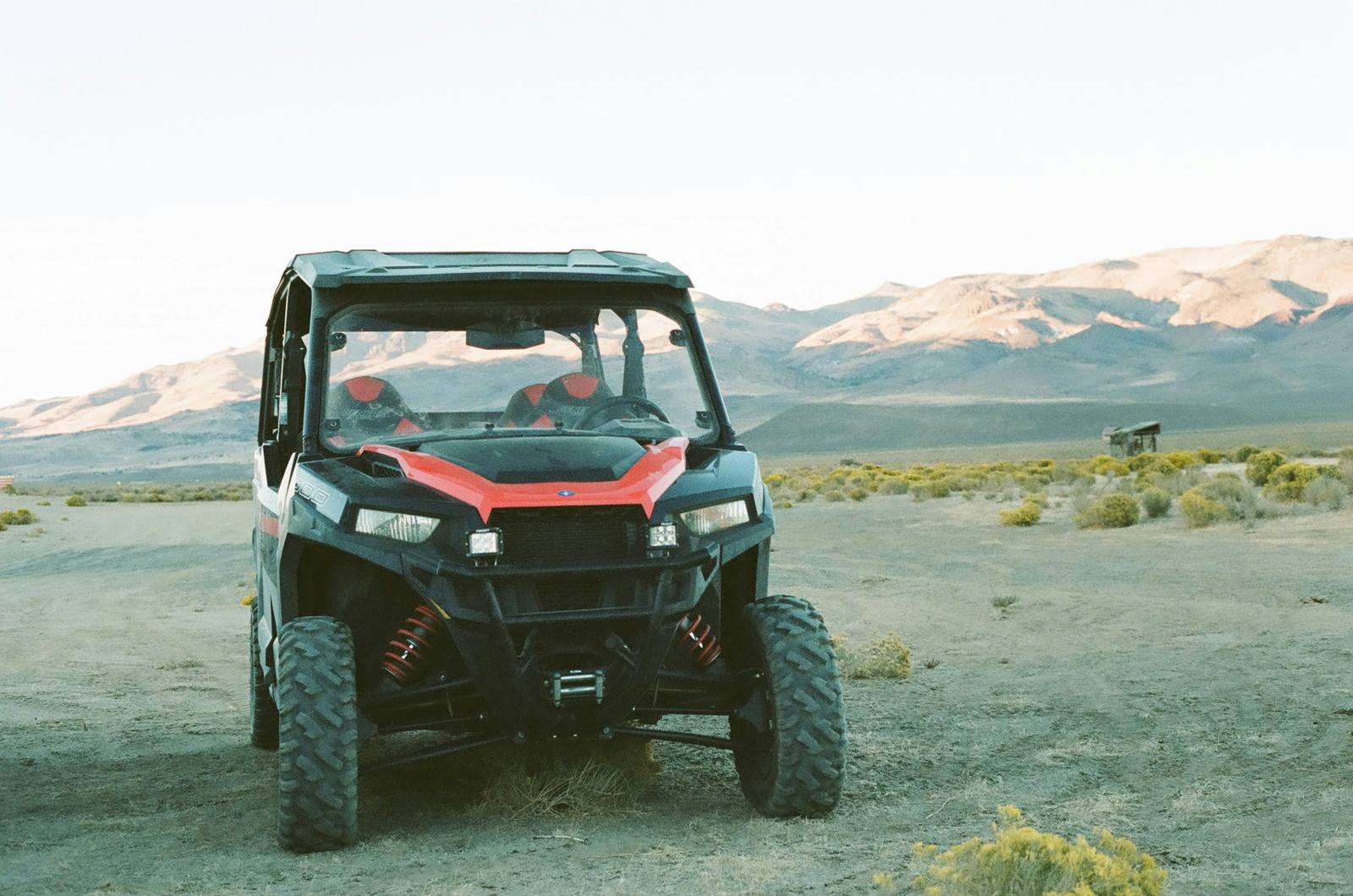 A side-by-side UTV parked in the desert with mountains behind it