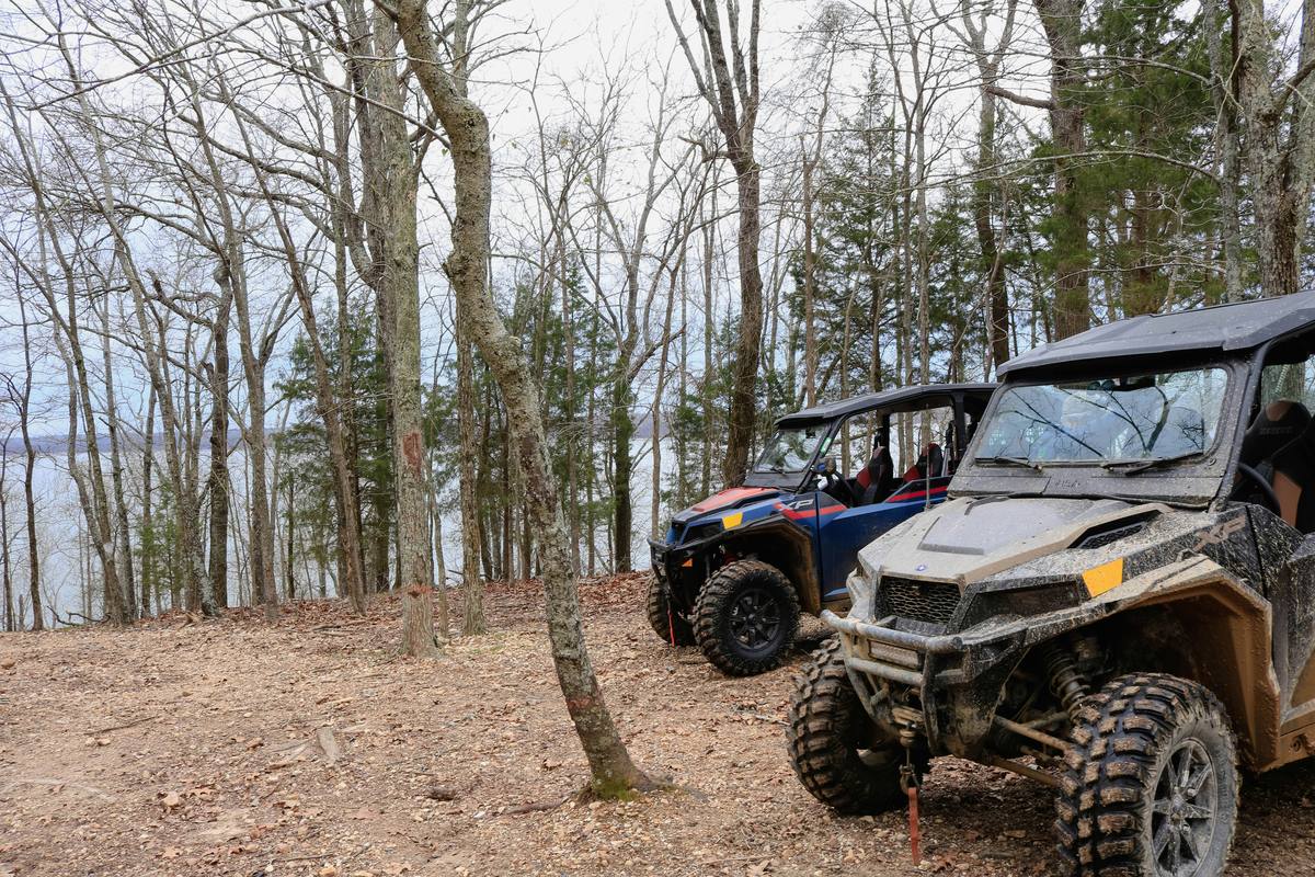 Two UTVs parked on a wooded trail overlooking a lake